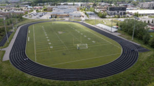 Aerial photo of St. Maximilian Kolbe CHS' football field and track, with the school building in the background